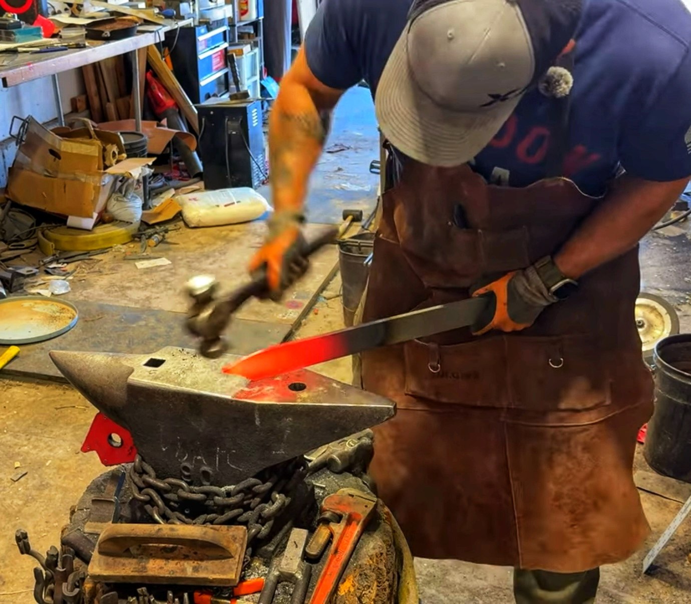 Bladesmith forging a glowing blade on an anvil at Atilivs Ironworks